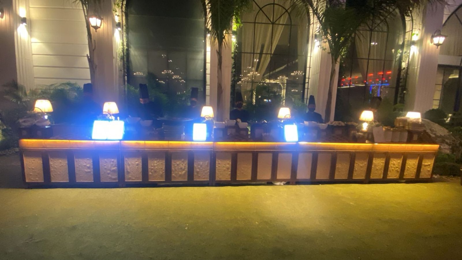 A long live counter line lit after dark at Azalea in Zirakpur, table lamps and crew along the full run