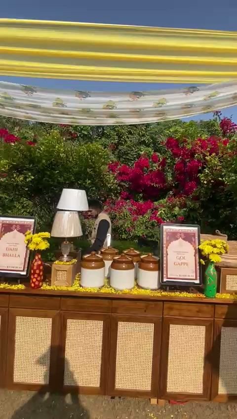 A daytime golgappa and dahi bhalla counter at The Oberoi Sukhvilas, matkas and marigolds along the front under a striped canopy